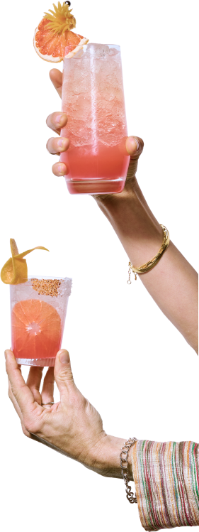 Hands holding grapefruit cocktails