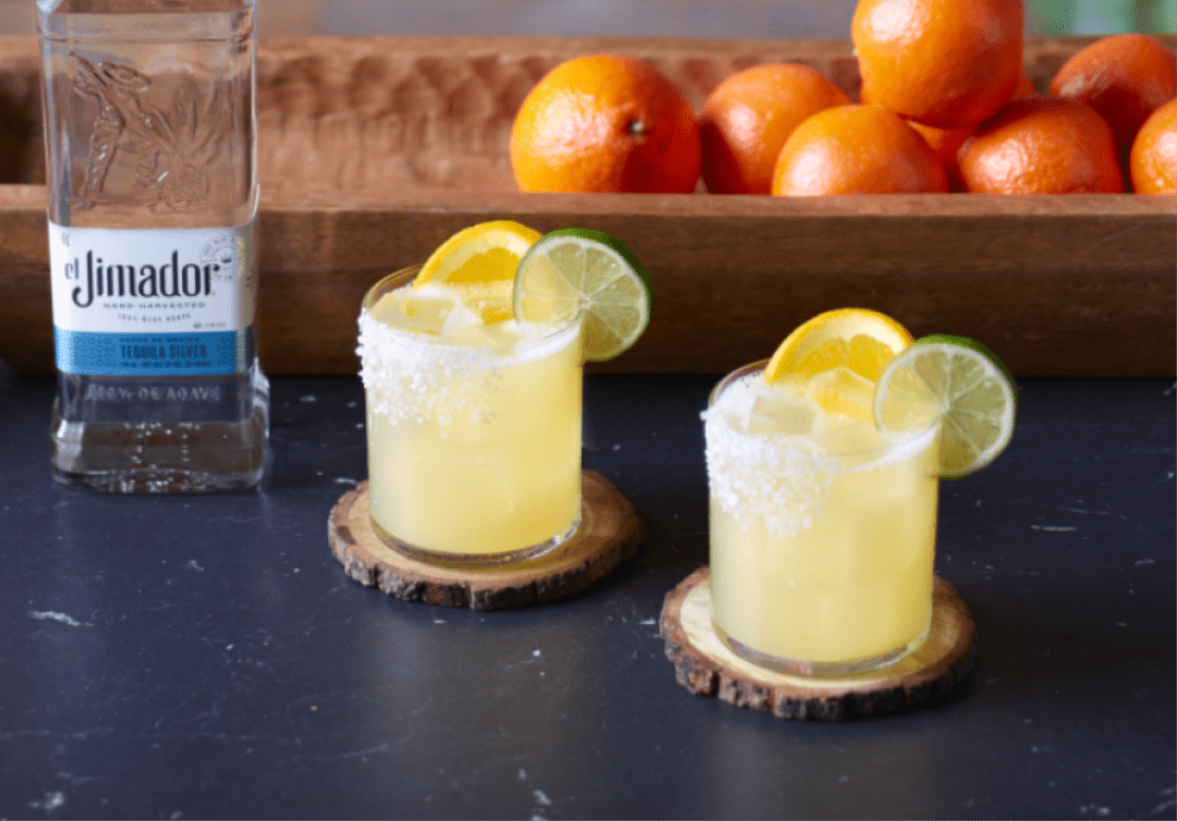 el Jimador Fresh Margarita cocktail on a table with oranges and el Jimador Silver bottle.