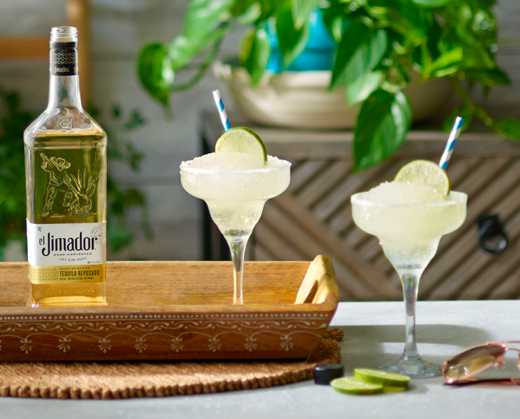 el Jimador Frozen Margarita cocktails on a table with a lime slices and el Jimador Reposado bottle.