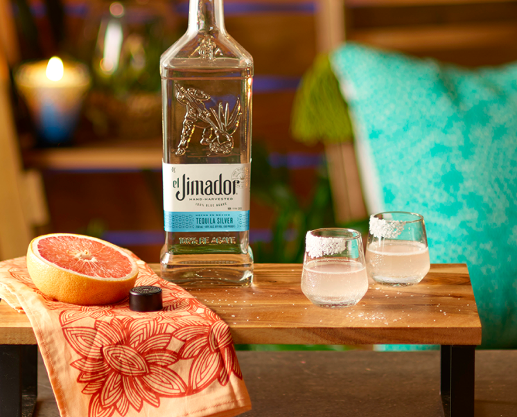 el Jimador Palomacita cocktail on a table with a grapefruit slice and el Jimador Silver bottle.