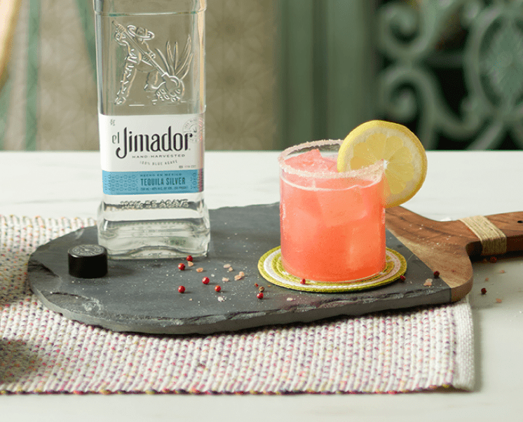 el Jimador Pink Peppercorn Margarita cocktails on a table with pink peppercorns and el Jimador Silver bottle.