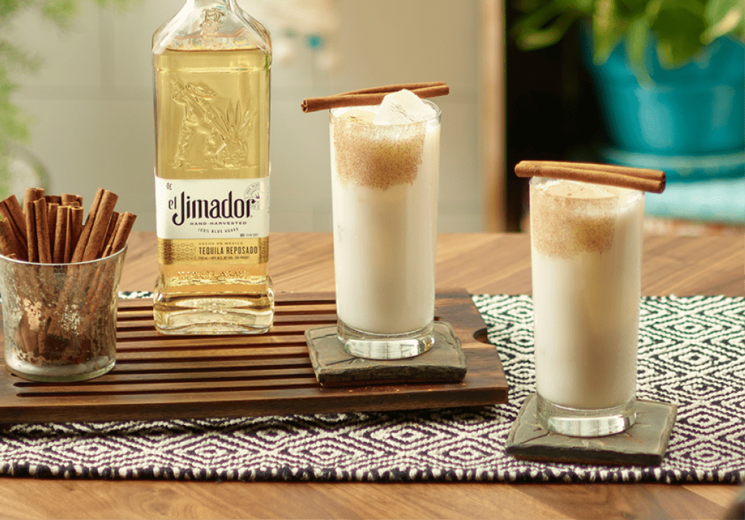 el Jimador Posada Horchata cocktails on a table with cinnamon sticks and el Jimador Reposado bottle.