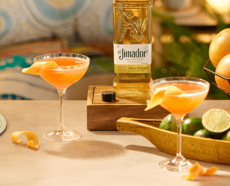 el Jimador Siesta cocktails on a table with a lime halves, orange twists and el Jimador Reposado bottle.