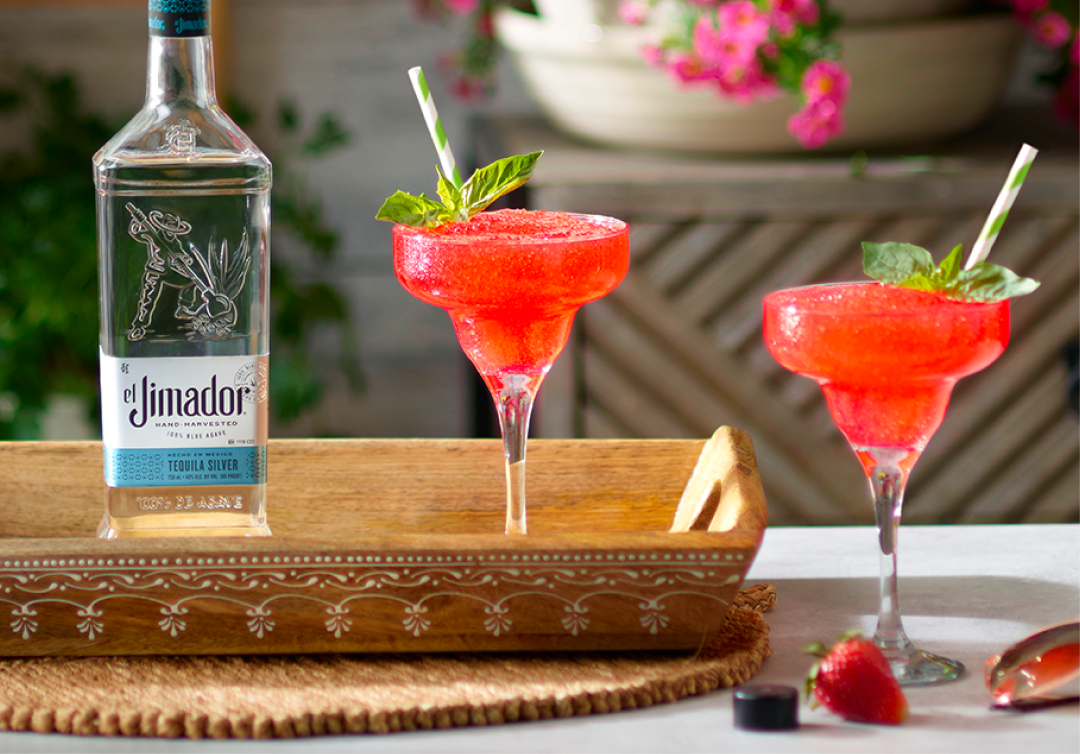 el Jimador Strawberry Margarita cocktails on a table with strawberries and el Jimador Silver bottle.